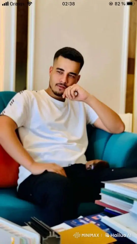 Casual Man Relaxing with Books and Cigarette in Teal Chair – AI Generated Video | Hailuo AI