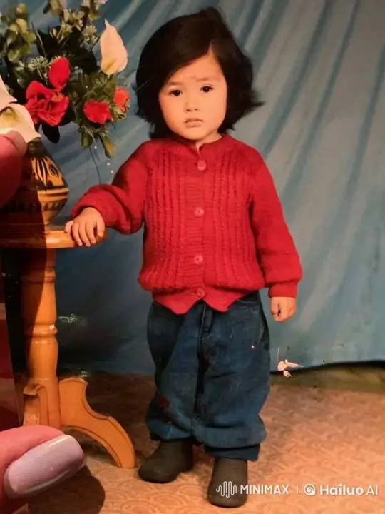 Child in Red Cardigan Stands Calmly by Flower Vase – AI Generated Video | Hailuo AI