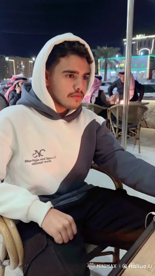 Contemplative Young Man Smokes at Lively Night Café – AI Generated Video | Hailuo AI