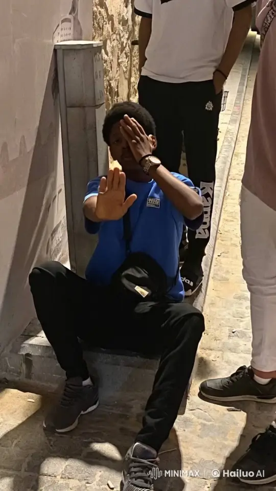 Young Man Sitting in Alley with Steady Hand Movements – AI Generated Video | Hailuo AI