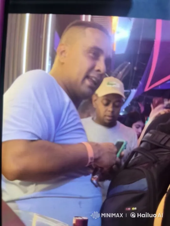 Nightclub Scene: Man on Smartphone Amidst Vibrant Atmosphere – AI Generated Video | Hailuo AI