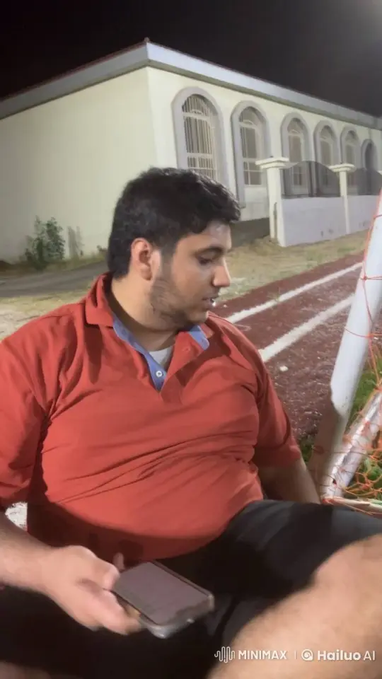 Nighttime Football Field: Man Smokes, Watches Phone – AI Generated Video | Hailuo AI