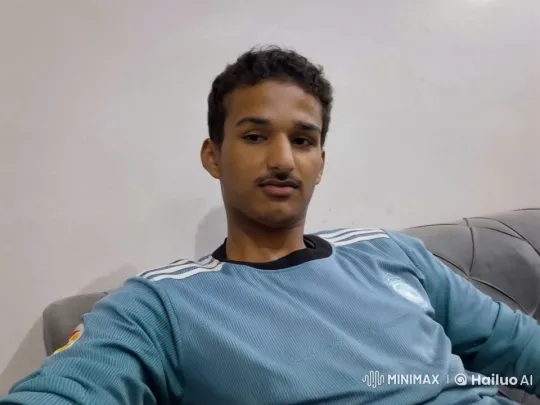 Young Man in Teal Jersey on Couch with Calm Demeanor – AI Generated Video | Hailuo AI