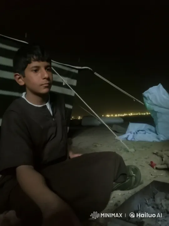 Contemplative Boy on Sand by Town Lights – AI Generated Video | Hailuo AI