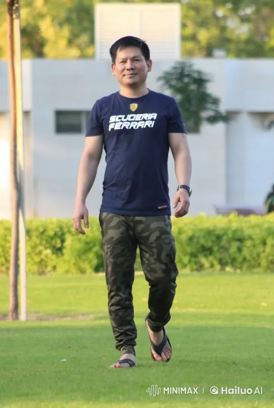 Man in Ferrari T-shirt Strolls on Manicured Grass – AI Generated Video | Hailuo AI