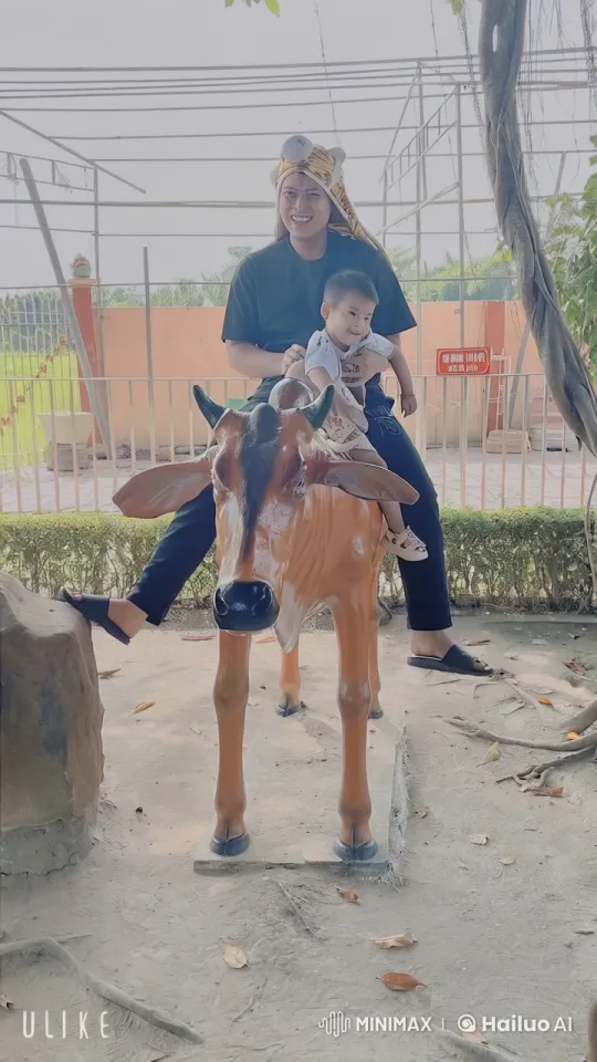 Man and Child Playfully Interact with Cow Statue – AI Generated Video | Hailuo AI