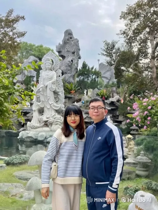 Couple Poses by Stone Statue in Tranquil Garden – AI Generated Video | Hailuo AI