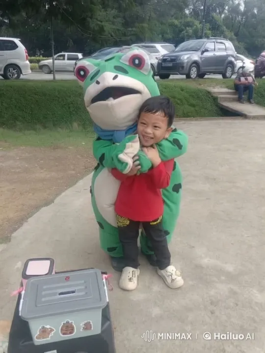 Child and Frog Mascot Playfully Spar in Park – AI Generated Video | Hailuo AI