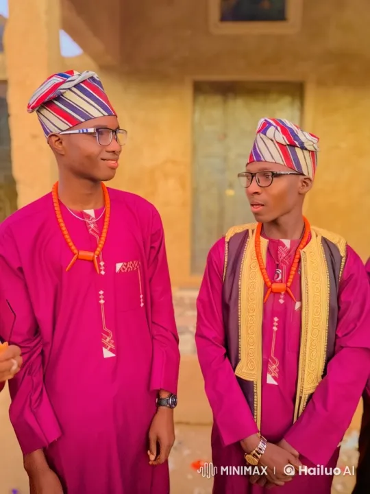 Two Men in Traditional Attire Stand by Earthen Wall – AI Generated Video | Hailuo AI