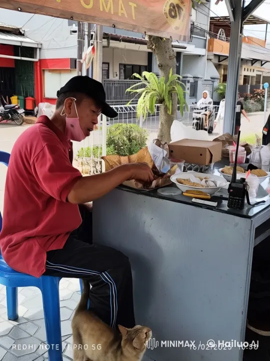 Man Eating at Street Stall with Curious Cat – AI Generated Video | Hailuo AI