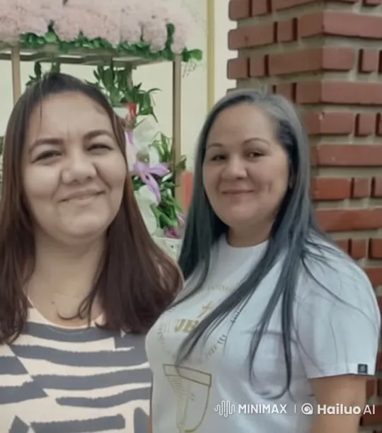 Two Women Embrace in Front of a Flower Arrangement – AI Generated Video | Hailuo AI