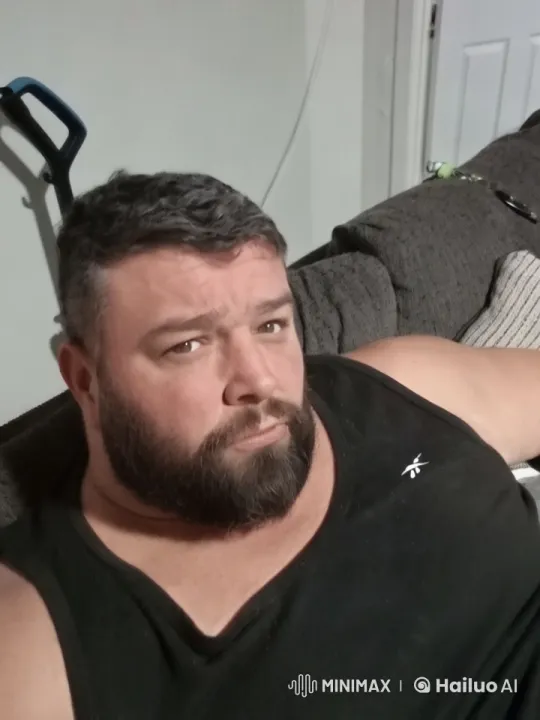 Man Laughs with Big Teeth on Brown Sofa in Soft-Lit Room – AI Generated Video | Hailuo AI