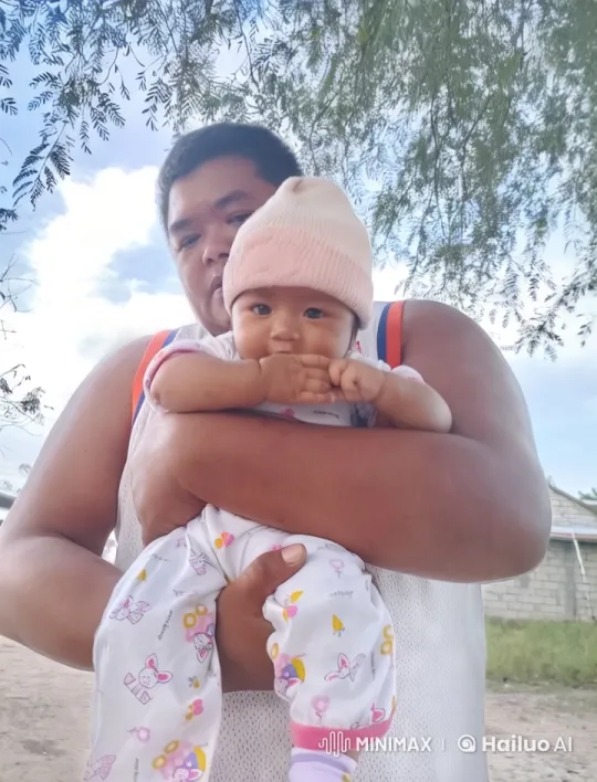 Person cradles baby in colorful outdoor setting – AI Generated Video | Hailuo AI