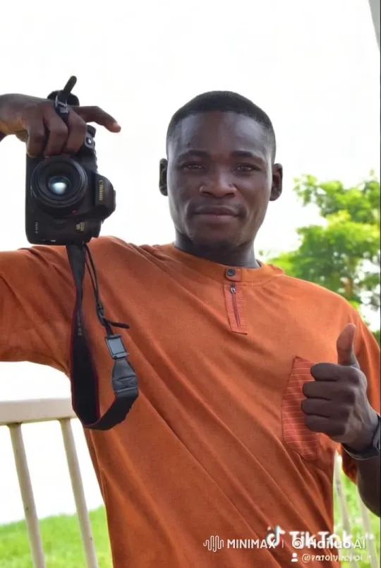Man in Orange Shirt Gives Thumbs-Up with Canon Camera – AI Generated Video | Hailuo AI