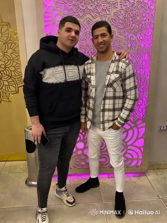 Two Men Pose Stylishly Against Artistic Wall – AI Generated Video | Hailuo AI