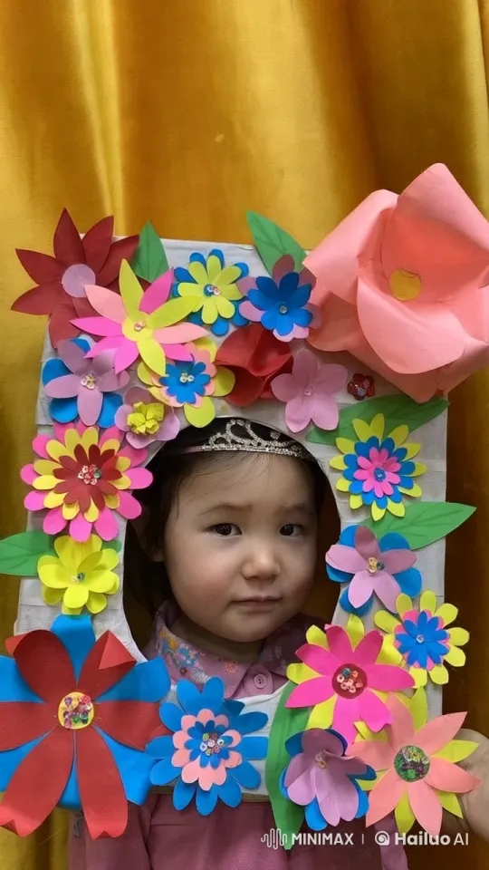 Child Showcases Handmade Floral Frame Against Elegant Curtain – AI Generated Video | Hailuo AI