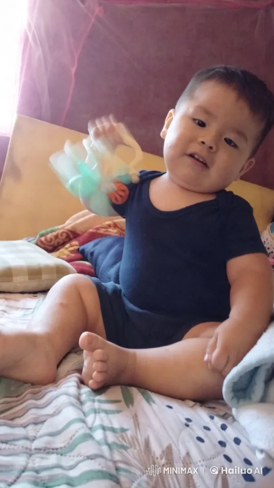Baby Playfully Shakes Toy on Colorful Bed – AI Generated Video | Hailuo AI
