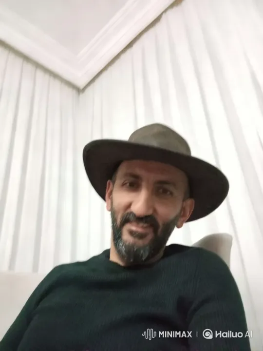 Dynamic Video of a Man in a Dark Hat with White Curtain Background – AI Generated Video | Hailuo AI