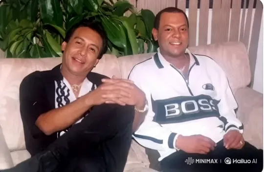 Two Men Greet Viewers on a Beige Couch with Nature Background – AI Generated Video | Hailuo AI