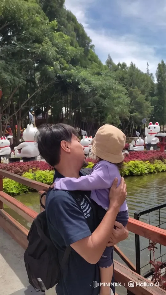 Man and Child Embrace Serenity in Park with Cat Statues – AI Generated Video | Hailuo AI