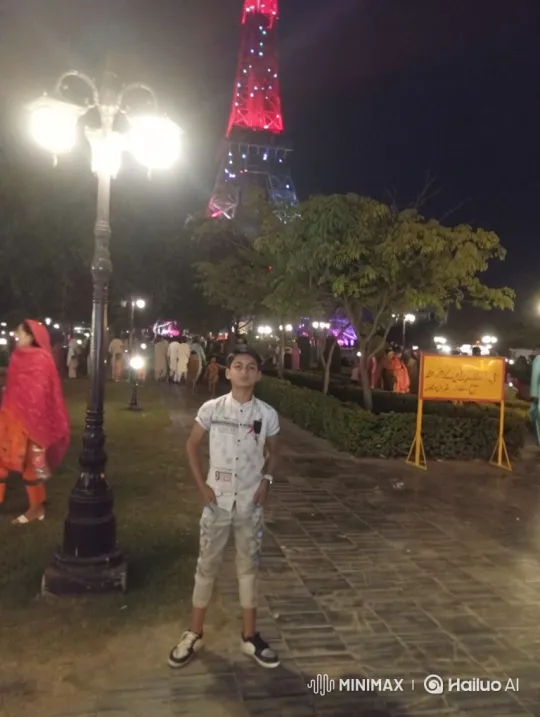 Boy Poses in Park at Night with Tower Background – AI Generated Video | Hailuo AI