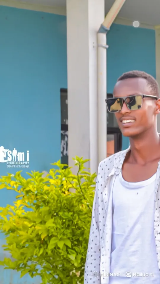 Young Man Smiles in Front of Building During Tracking Shot – AI Generated Video | Hailuo AI