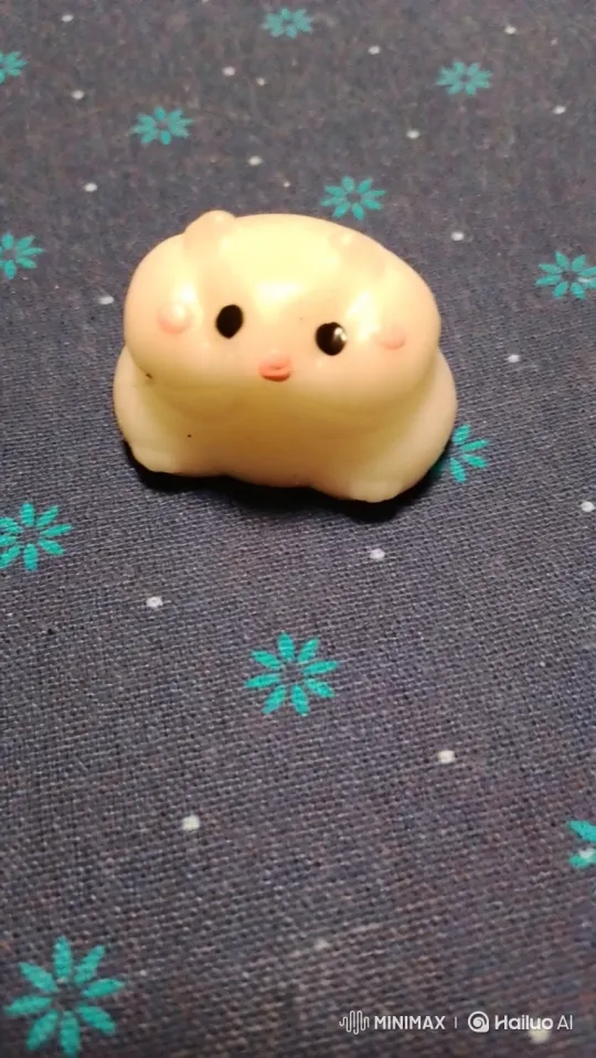 Hamster Figurine Enjoying Cheese on Textured Fabric – AI Generated Video | Hailuo AI