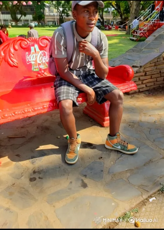 Contemplative Young Man on Coca-Cola Bench in Park – AI Generated Video | Hailuo AI