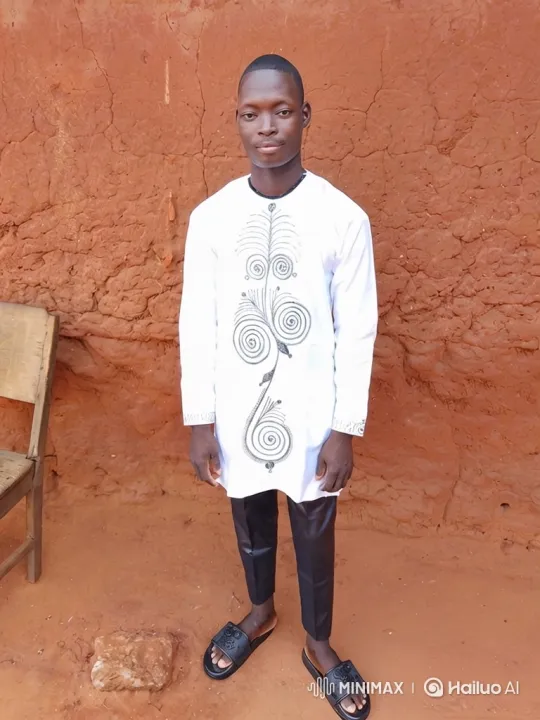 Young Man in Embroidered Tunic Stands by Earthen Wall – AI Generated Video | Hailuo AI