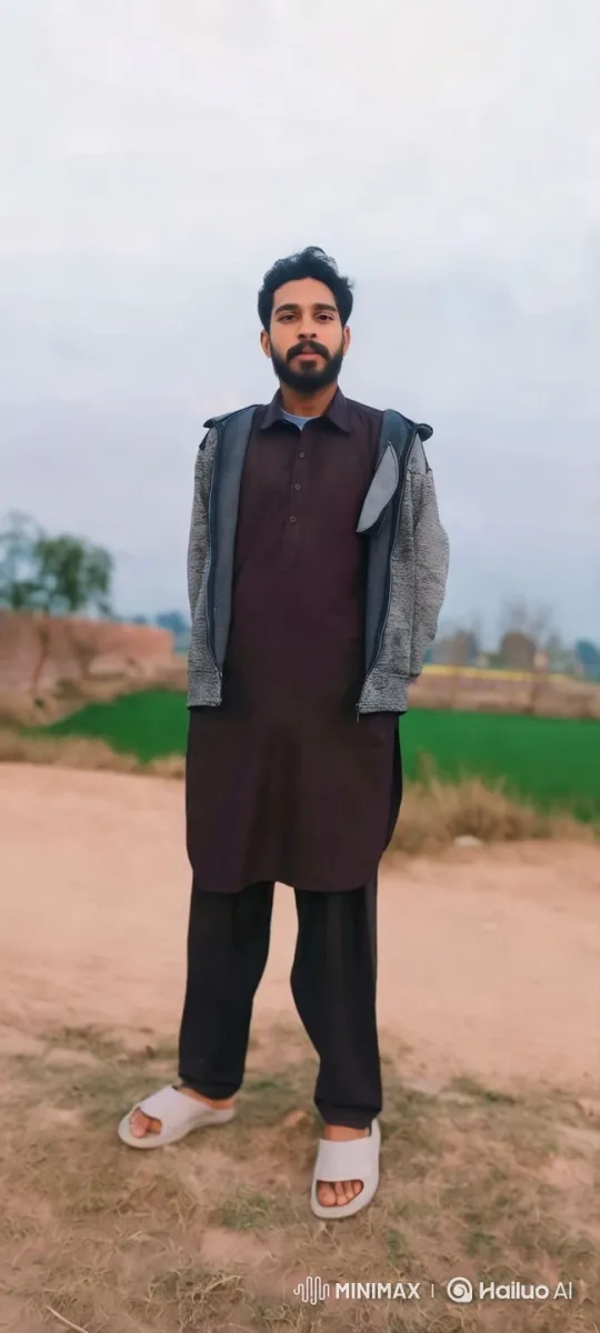 Confident Man in Traditional Attire Amidst Serene Rural Landscape – AI Generated Video | Hailuo AI