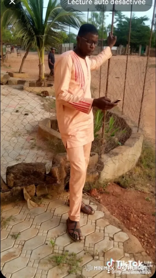 Man in Peach Outfit Stands by Fence at Sunset – AI Generated Video | Hailuo AI