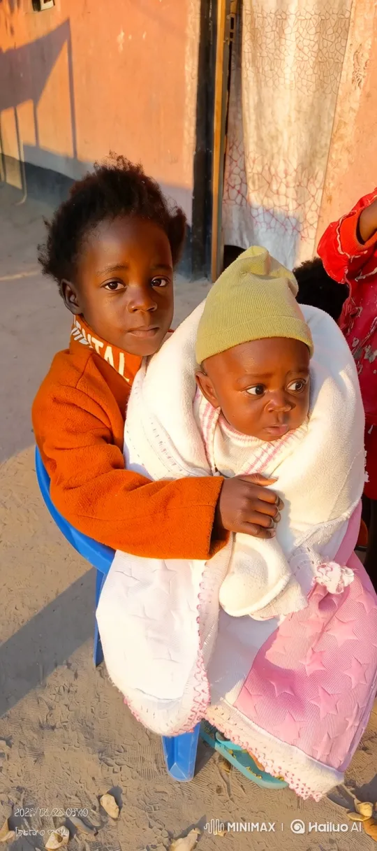 Young Child Tenderly Holds Baby in Golden Light – AI Generated Video | Hailuo AI
