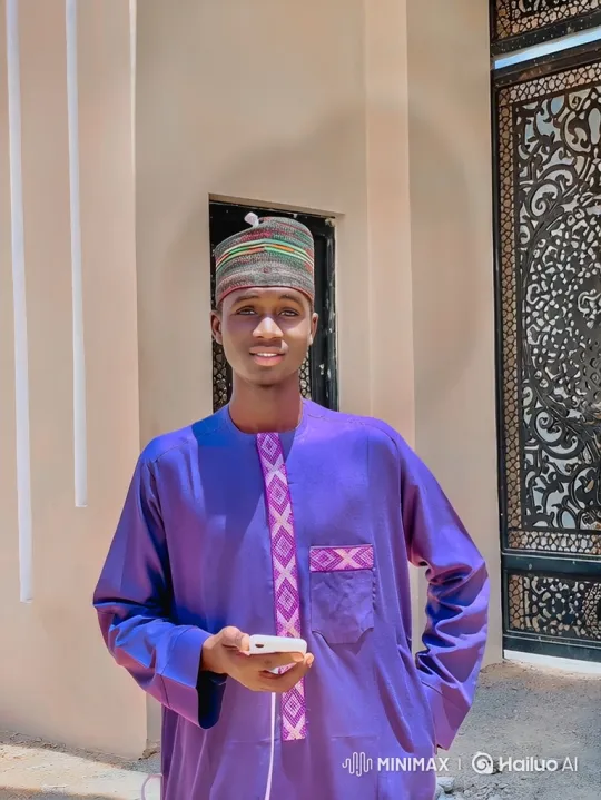 Young Man in Purple Embroidered Garment Smiles at Camera – AI Generated Video | Hailuo AI