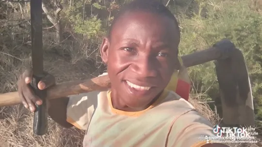 Young Black Man Smiling with Hoe in Sunny Field – AI Generated Video | Hailuo AI