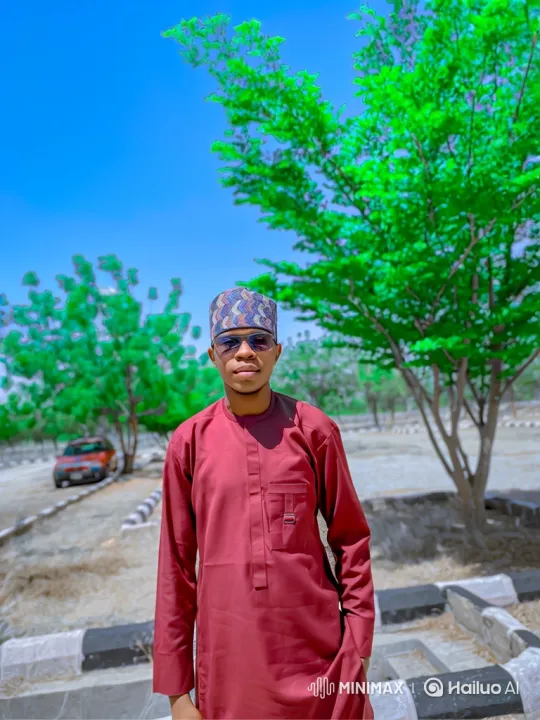 Young Man in Maroon Tunic, Serene Smile Amidst Rustling Leaves – AI Generated Video | Hailuo AI
