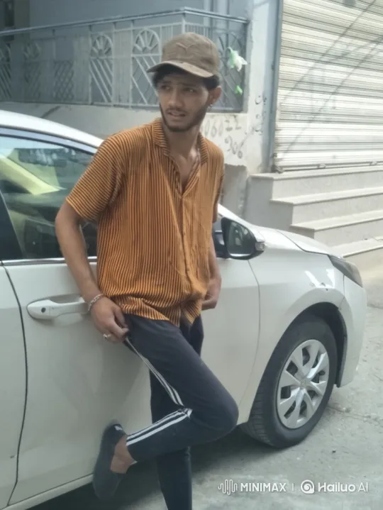Young Man Reflects by Car, Shifts Posture, Meets Camera's Gaze – AI Generated Video | Hailuo AI