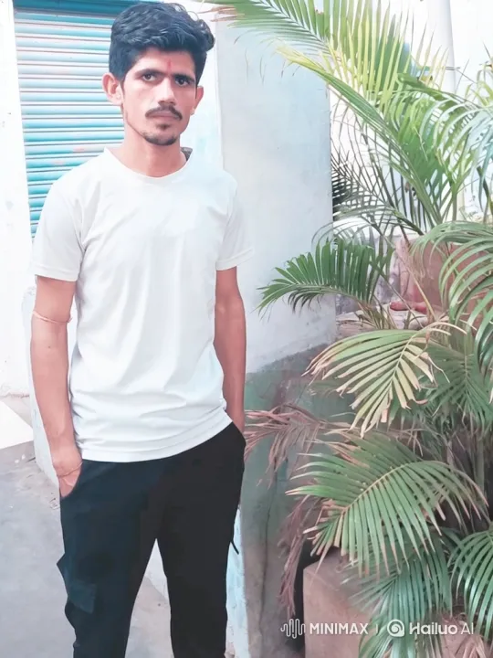 Young Man Stands Calmly by Potted Plant in Breezy Outdoor Setting – AI Generated Video | Hailuo AI