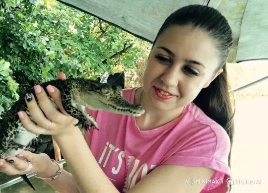 Young Woman Examines Small Crocodile Outdoors – AI Generated Video | Hailuo AI
