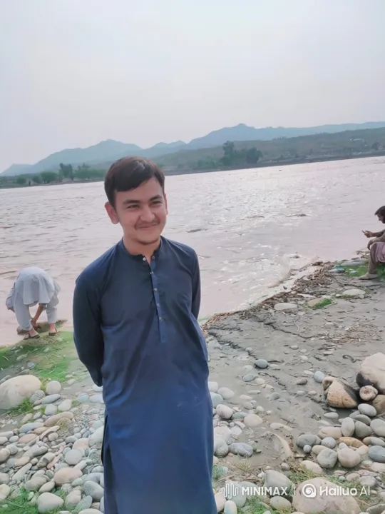 Young Man on Shoreline with River and Mountains – AI Generated Video | Hailuo AI