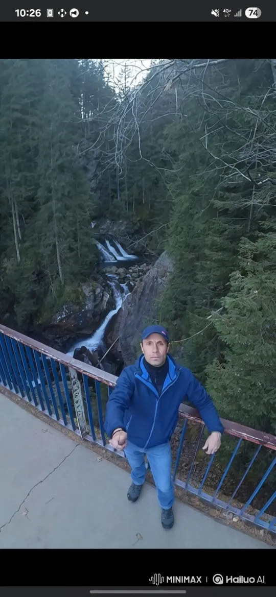 Man Enjoying Scenic View on Bridge with Waterfall – AI Generated Video | Hailuo AI
