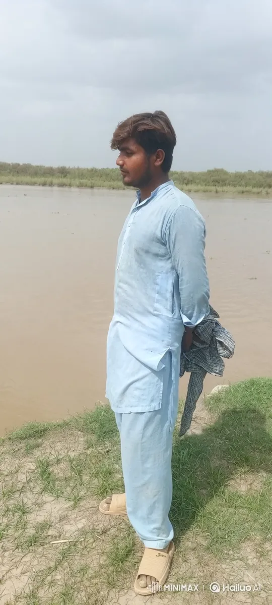 Young Man Contemplates by Muddy River with Gentle Breeze – AI Generated Video | Hailuo AI