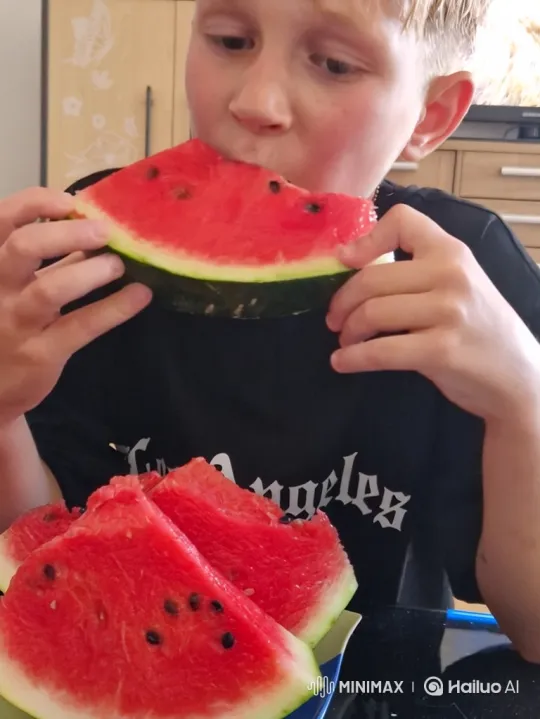 Boy Enjoying Watermelon Slice in Kitchen – AI Generated Video | Hailuo AI