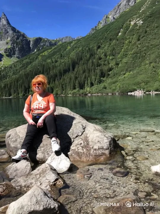 Woman Reflects by Alpine Lake Amidst Majestic Mountains – AI Generated Video | Hailuo AI